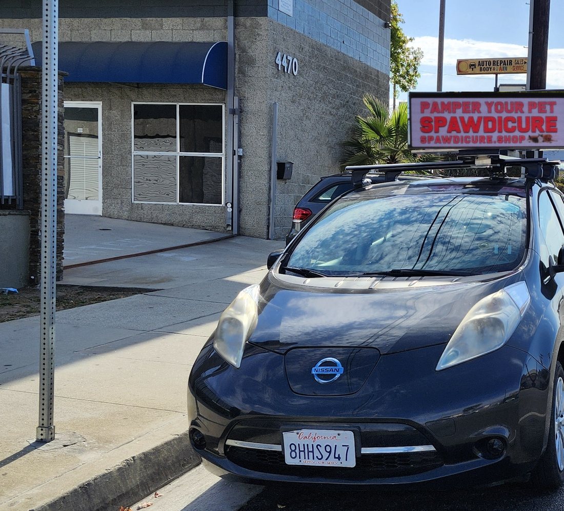 A Quantum OOH Digital Topper mounted on a parked car at a Los Angeles storefront, screen facing traffic